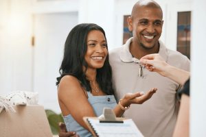 Happy couple, real estate and property with keys from realtor or homeowner for buying, mortgage loa